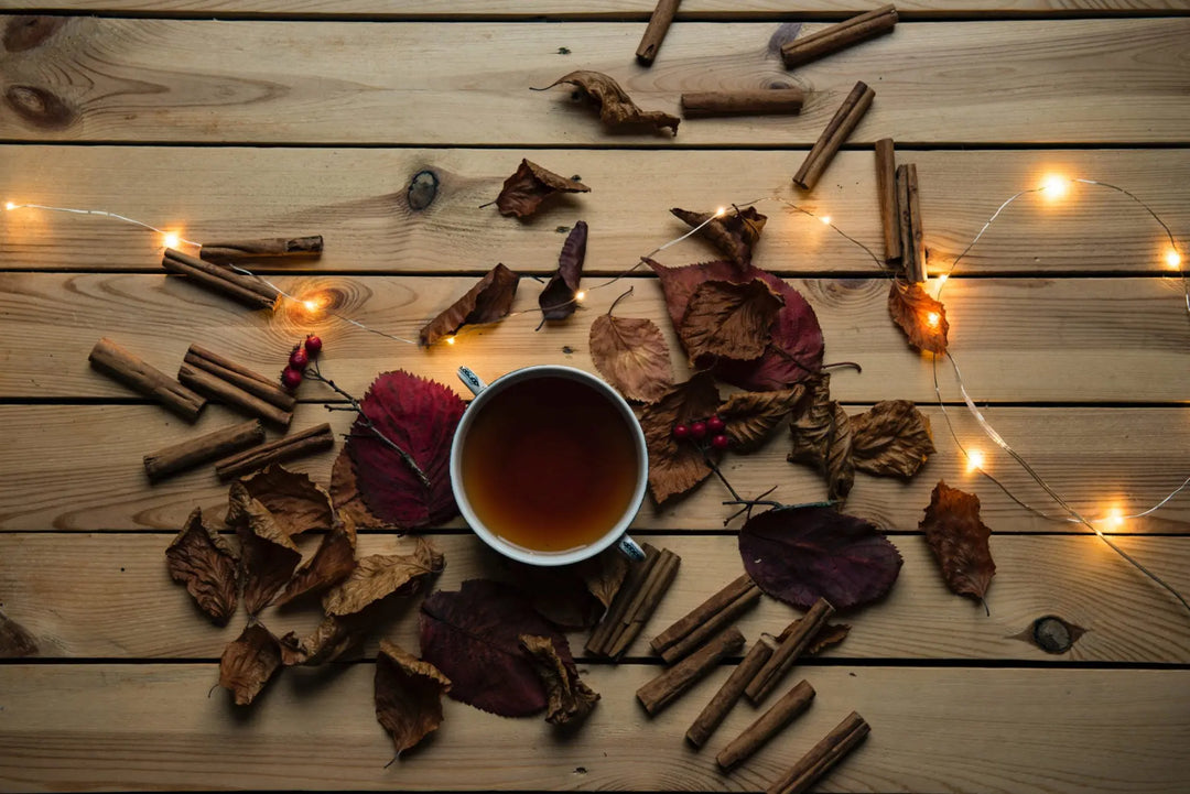 Tasse de tisane chaude entourée de feuilles d'automne.